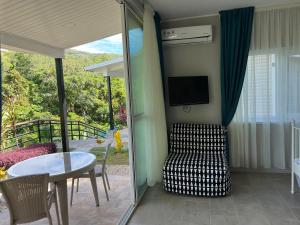 sala de estar con mesa, silla y TV en Takamakasky Villas en Takamaka