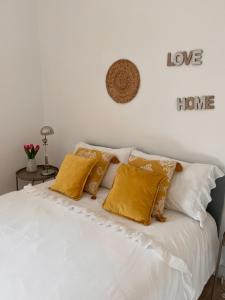 1 cama blanca con almohadas amarillas y un letrero en la pared en Teodósio-Zona Central- Ar condicionado-Perto Praias, en Setúbal