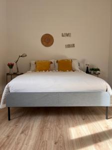 1 dormitorio con 1 cama con sábanas blancas y almohadas amarillas en Teodósio-Zona Central- Ar condicionado-Perto Praias en Setúbal