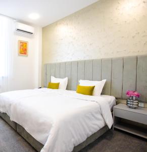 ein Schlafzimmer mit einem großen weißen Bett mit gelben Kissen in der Unterkunft Benefice Hotel Yerevan in Yerevan