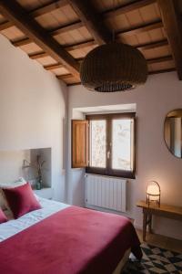 a bedroom with a bed with a red blanket and a window at L'Olivera, Casa a Rupià in Rupiá