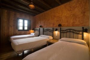 a group of four beds in a room at A Reboleira - Casa Nuñez in Fonfría