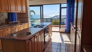 een keuken met een wastafel en uitzicht op de oceaan bij Villa @ 19 Palm with spectacular sea views in Jeffreys Bay