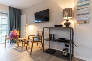 ein Wohnzimmer mit einem Tisch und Stühlen sowie einem TV in der Unterkunft Beach Lodge Beach Lodge Appartement 6 in Sankt Peter-Ording