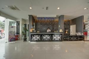 a woman standing behind a counter in a lobby at Arenaa Deluxe Hotel in Melaka