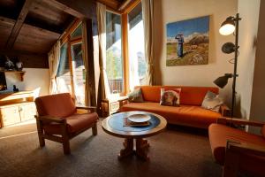 a living room with an orange couch and a table at Chesa Munteratsch 1 1 2-Zimmerwohnung 609 Typ D in Silvaplana
