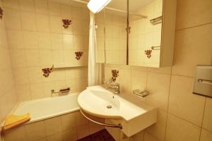 a white bathroom with a sink and a bath tub at Chesa Munteratsch 1 1 2-Zimmerwohnung 409 Typ C in Silvaplana