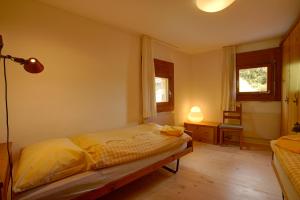 ein Schlafzimmer mit einem Bett und einem Schreibtisch und zwei Fenstern in der Unterkunft Chesa Munteratsch 2-Zimmerwohnung 410 Typ E in Silvaplana
