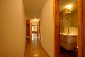 einen Flur eines Badezimmers mit einem Waschbecken und einem Spiegel in der Unterkunft Chesa Munteratsch 2-Zimmerwohnung 410 Typ E in Silvaplana + 63 Fotos