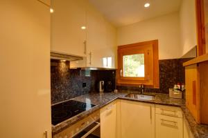 a kitchen with white cabinets and black counter tops at Chesa Munteratsch 2-Zimmerwohnung 301 Typ E in Silvaplana +66 photos