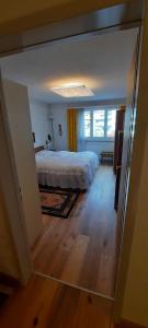 クロスタースにあるFerienwohnung nähe Madrisaのウッドフロアのベッドルーム1室(白いベッド1台付)