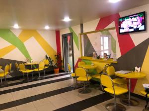 a restaurant with yellow chairs and tables and a tv at Саквояж Вокзал in Lviv