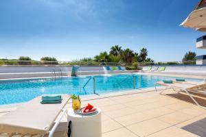 - une piscine avec une table et des chaises à côté de la piscine dans l'établissement Aparthotel Odissea Park, à Santa Susanna