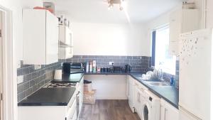 una cocina con armarios blancos y encimeras negras en Double Bedroom In Withington, M20. 1 DB Bed, RM 1 en Mánchester