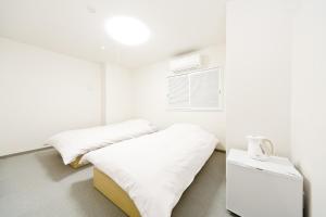 a white room with two beds and a window at Business Hotel Yamashiro in Tokyo