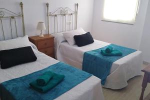 1 dormitorio con 2 camas y toallas verdes. en Apartamento ALAZAN a 50 metro de la playa, en Málaga