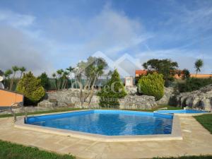 una piscina en un patio con una pared de piedra en Villa Arrifes, en Reguengo Grande