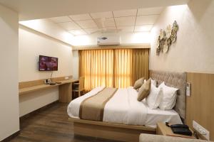 a hotel room with a bed and a desk at Hotel PTC in Indore