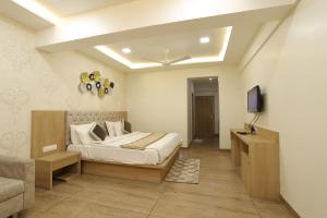 um quarto com uma cama, uma televisão e um sofá em Hotel PTC em Indore