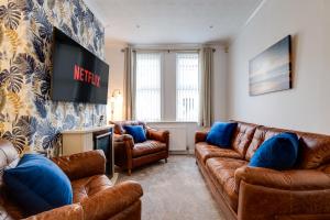 a living room with leather couches and a tv at Sandy House in Scarborough