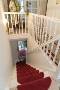 un escalier avec moquette rouge dans une maison dans l'établissement Hotel Petit Wannsee, à Berlin