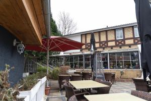 eine Terrasse mit Tischen, Stühlen und einem Sonnenschirm in der Unterkunft Hotel Petit Wannsee in Berlin