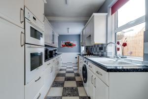 a kitchen with white cabinets and a sink at Sandy House in Scarborough