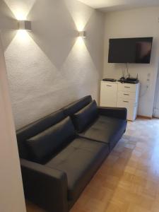 uma sala de estar com um sofá preto e uma televisão de ecrã plano em 37m² 1,5 Zimmer mit Terrasse und super Badezimmer em Tangstedt