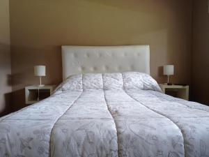 1 dormitorio con 1 cama blanca grande y 2 lámparas en Musas con Pileta NO ACEPTO GRUPO DE JOVENES en Pinamar