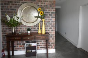 a table with vases and a mirror on a brick wall at OnQ Accommodation in Bellville