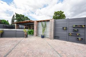 a house with a fence and a brick driveway at OnQ Accommodation in Bellville