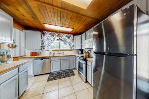 a kitchen with white cabinets and a wooden ceiling at By the Water in Pacific City