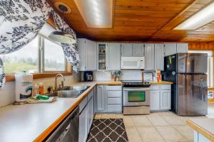a kitchen with white appliances and a wooden ceiling at By the Water in Pacific City +9 photos