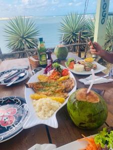 una mesa con platos de comida encima en Sonia Flats Arituba Tropical - Flat vista mar em frente à Praia de Camurupim, en Nísia Floresta