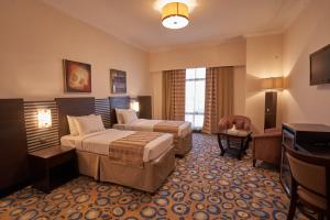 a hotel room with two beds and a television at Al Hidayah Towers Hotel in Makkah