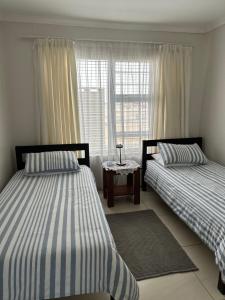two beds in a room with a window at Sandy Shores 3 Henties in Hentiesbaai