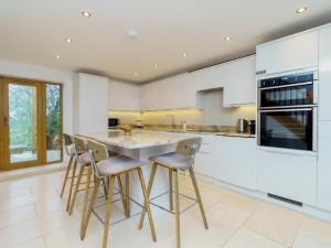 uma cozinha com armários brancos e uma grande ilha com bancos em Pass the Keys Modern 3 bed home with offstreet parking em Bath