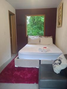 Habitación pequeña con 2 camas y sofá en Suítes Caminho das Rosas Experiência na Montanha en Guapimirim