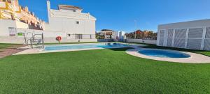 a backyard with a swimming pool and green grass at Chalet Francisco in San Juan de los Terreros