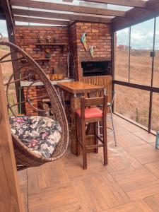 eine Veranda mit einem Tisch, Stühlen und einem Kamin in der Unterkunft Chalé Guadalupe - Condomínio Altos da Serra in Bom Jardim da Serra