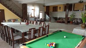 a pool table in a living room with a table and chairs at Casa de vacanta La Ticu in Cîndeşti