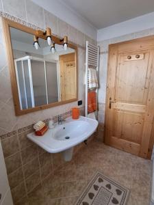 uma casa de banho com um lavatório, um espelho e uma porta em Appartamento ai larici, rustico ed elegante em Varena