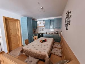 a room with a table and a kitchen with blue cabinets at Appartamento ai larici, rustico ed elegante in Varena
