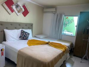 two beds in a small room with a window at Pousada Caminho do Pontal in Arraial do Cabo