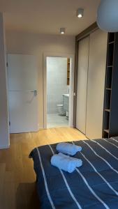 a bedroom with a bed with blue sheets and a bathroom at The Comfy Nest in Cluj-Napoca