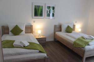 een slaapkamer met 2 bedden en groene en witte handdoeken bij greenpartment Boardinghousehotel Kelheim in Kelheim