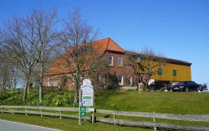un panneau dans l'herbe devant une maison dans l'établissement Schäferhof Dircks Fewo 3, à Westerhever