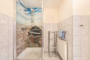 La salle de bains est pourvue d'une douche et d'une peinture représentant un bateau. dans l'établissement Schäferhof Dircks Fewo 3, à Westerhever