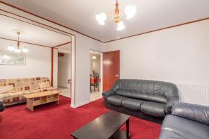 ein Wohnzimmer mit einem Ledersofa und einem Tisch in der Unterkunft Marmottes Furnished flat in Annecy
