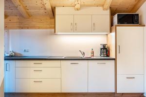 una cocina con armarios blancos y fregadero en Mittnackerhof Apartment Melisse, en Sarentino
